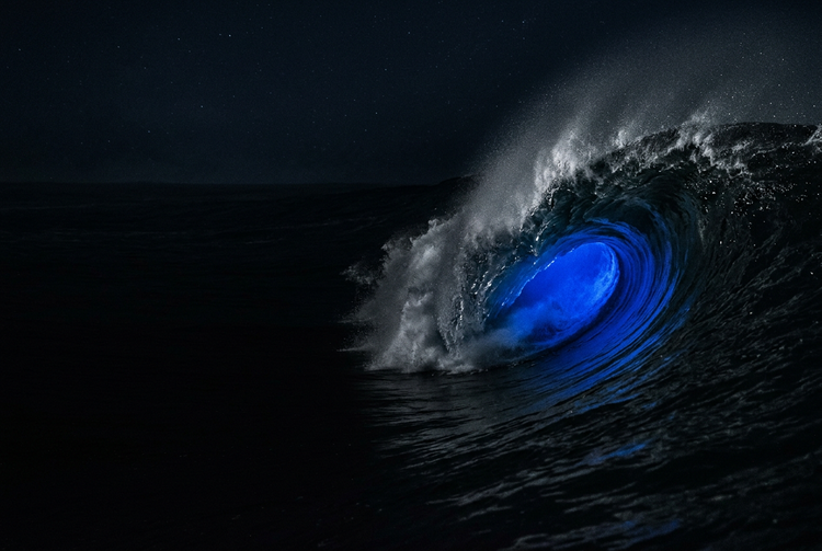 Dark wave breaking at night with blue light